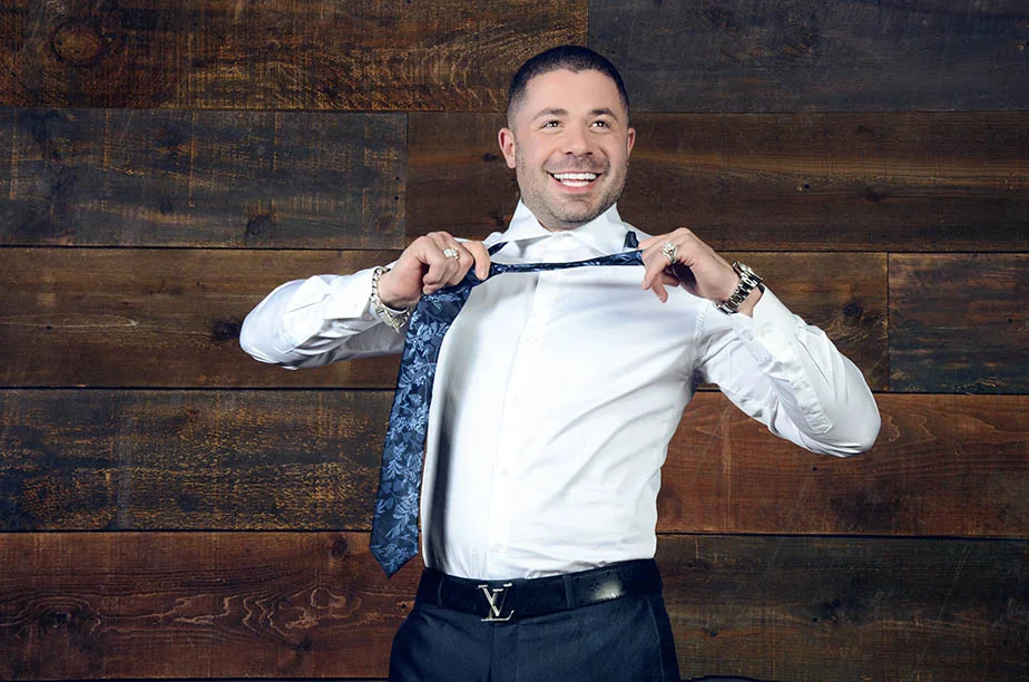Jeffrey Wachman adjusting his tie in a studio portrait